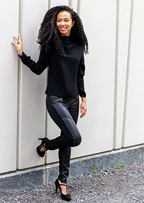 
                  
                    Black Suko Jeans Ponte Leggings for Women with faux leather front, angled zippered pockets. Model in front of wall
                  
                