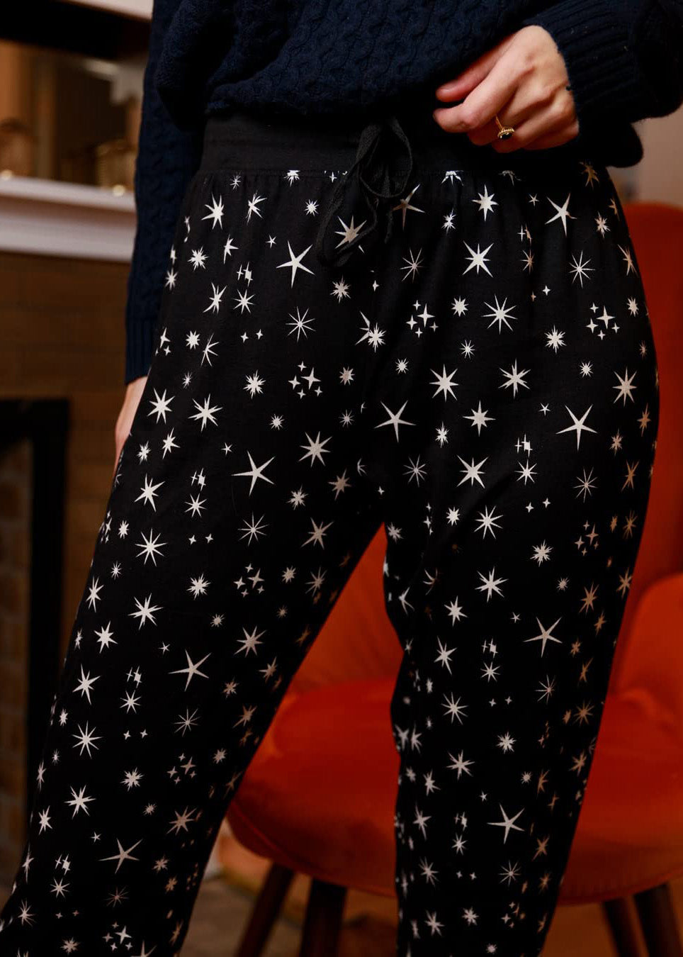 
                  
                    PJ joggers with soft velvety texture, stretch, elastic waistband, drawstring, and stylish ankle cuff. This pattern is scattered stars, of varied size and shape, white, on black stars on a black background.
                  
                