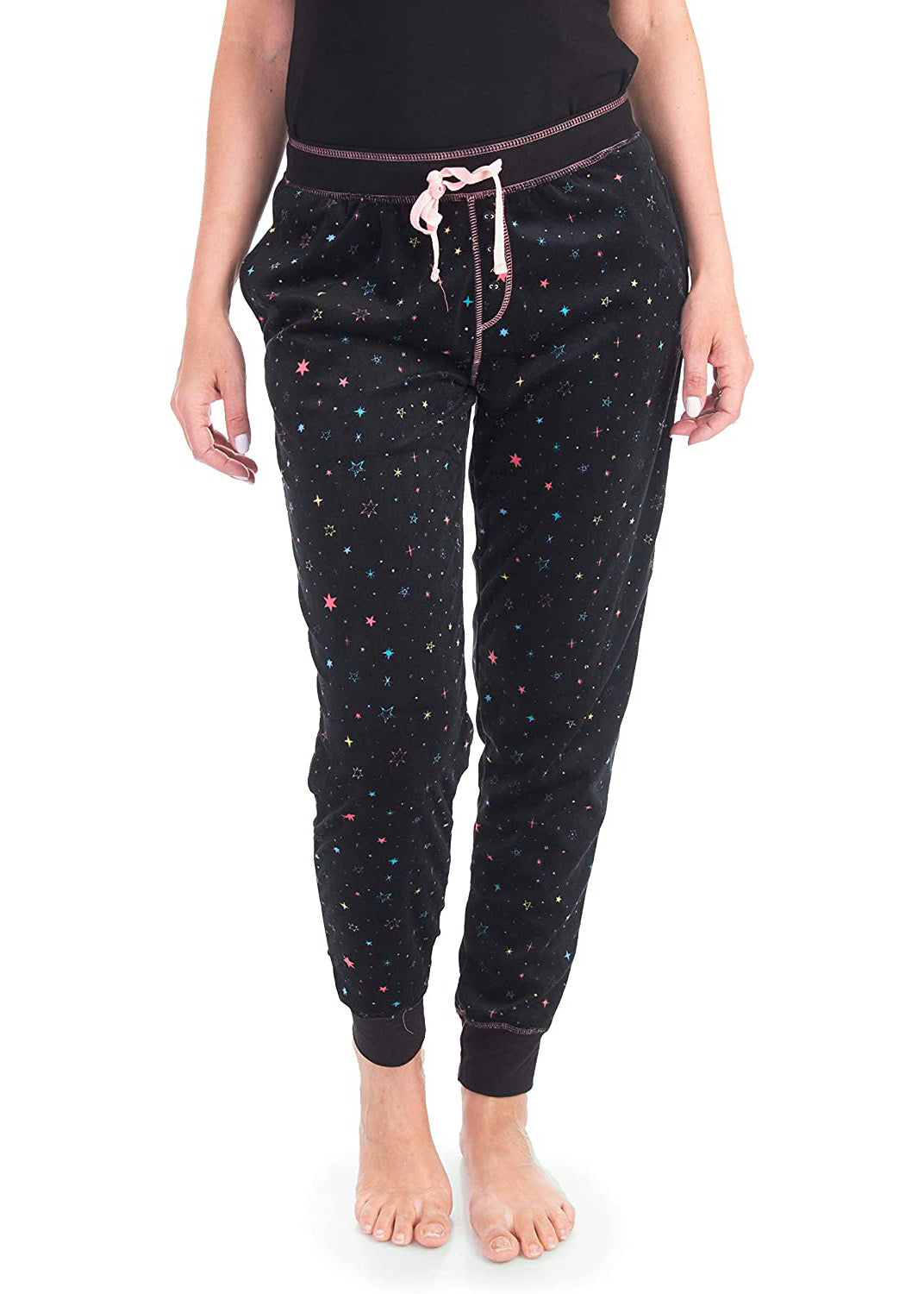 PJ joggers with soft velvety texture, stretch, elastic waistband, drawstring, and stylish ankle cuff. This pattern is scattered stars, very small pink, blue, yellow stars on a black background. The product has a pink overstitch.