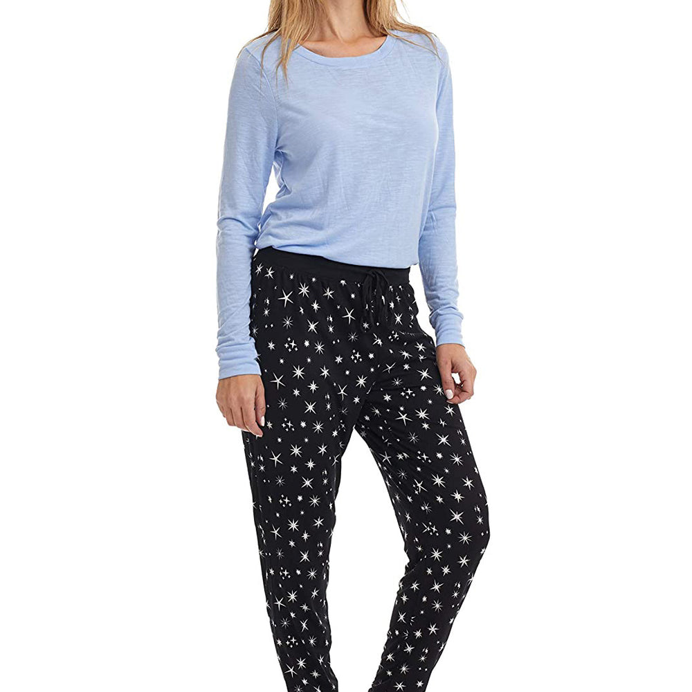 
                  
                    PJ joggers with soft velvety texture, stretch, elastic waistband, drawstring, and stylish ankle cuff. This pattern is scattered stars, of varied size and shape, white, on black stars on a black background. The model is matching it with a light blue top. 
                  
                